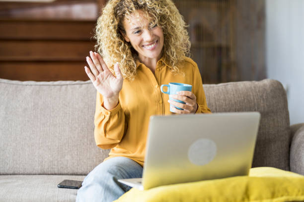 istock Full Length Of Woman Using Mobile Phone While Sitting On Sofa 1341109324