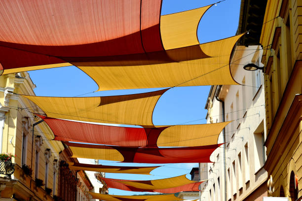 pastellfarbene sonnenschutzseken aus leinwand über der alten europäischen einkaufsstraße. - shade sail awning textile stock-fotos und bilder