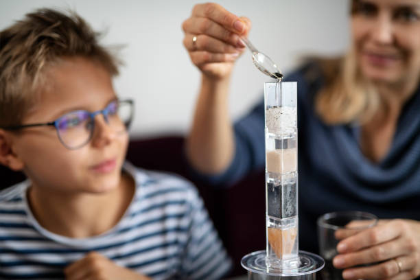 Close-up of a schoolgirl carefully dropping a chemical using dropper into a test tube in science class