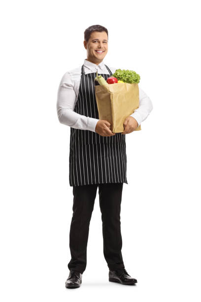 retrato de cuerpo entero de un joven chef con un delantal y sosteniendo una bolsa de supermercado - buttler fotografías e imágenes de stock