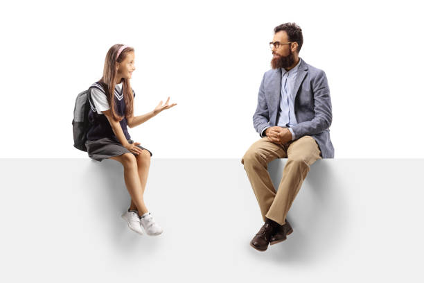 istock Schoolgirl and a bearded man sitting on a blank panel and talking 1341112385