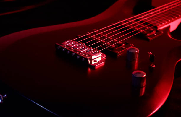 Black electric guitar illuminated by red light