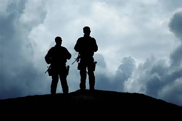 Silhouette of soldiers standing on a hilltop.