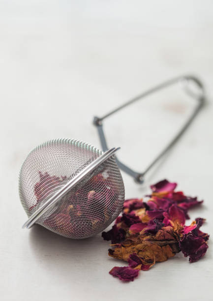 istock Rose petals craft grade tea with strainer infuser on white. 1341123055
