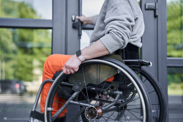 Physically challenged girl moving herself at the wheelchair and opening doors stock photo