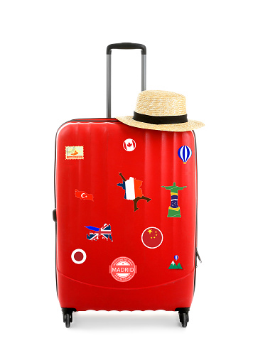 Maleta roja con pegatinas de viaje sobre fondo blanco photo
