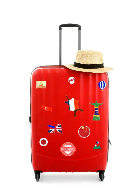 Photo of Red suitcase with travel stickers on white background