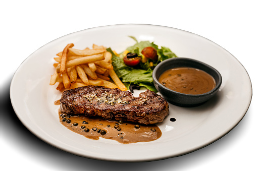 A White Plate of Medium Rare Beefsteak served with French Fried and Salad Cut Out White Background