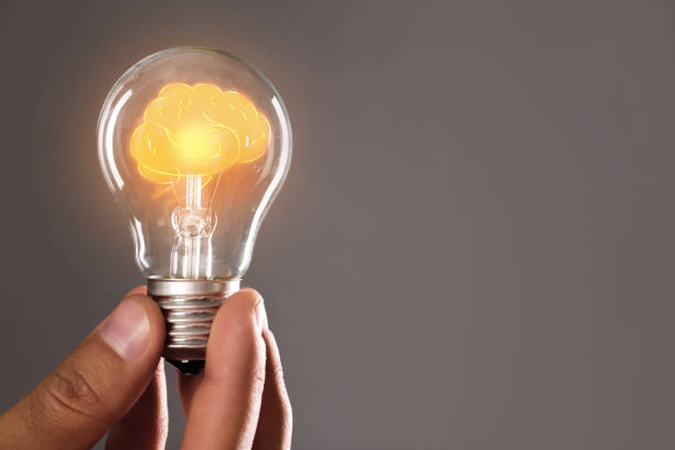 istock Man holding light bulb with shining brain inside against grey background, space for text. Idea generation 1341127979