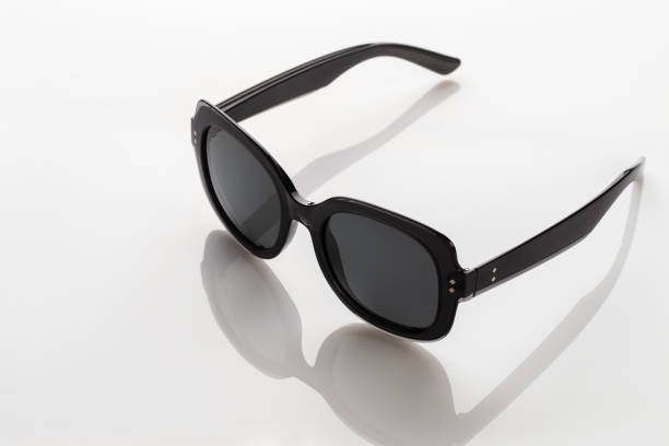 istock Sunglasses on a white reflective surface. Fashionable, stylish accessories.  Use it for a vacation or summer concept. 1341128039