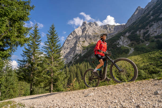 senior woman with electric mountain bike in the austrian alps beautiful active senior woman with electric mountainbike in the spectacular Mountains of Raintal Valley, a side valley of Lechtal, Tyrol, Austria mountain biking stock pictures, royalty-free photos & images