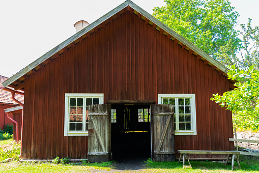 Vira Bruk, Sweden - July 5, 2021: Facade summer view of a old red traditional wooden barn at the open-air museum Vira Bruk Sweden July 5, 2021.