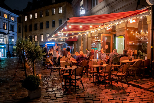 Stockholm, Sweden - August 27, 2021: Night scene with guests eating and drinking at a restaurant outdoors in Gamla Stan Stockholm Sweden August 27, 2021.