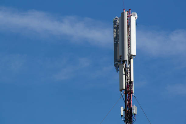 istock Mobile cell phone tower against the background of a blue sky and white cloud. Telecommunication TV tower. Cellular antenna. Wi-fi transmitter and receiver module 1341133572