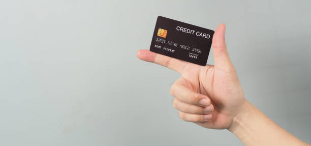 istock Hand is holding black credit card isolated on grey background. 1341133635