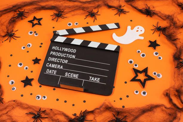 istock Clapper board in spider webs, spiders, ghost, eyes on orange background. 1341140765