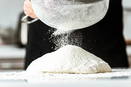 Adding flour to dough using sieve.