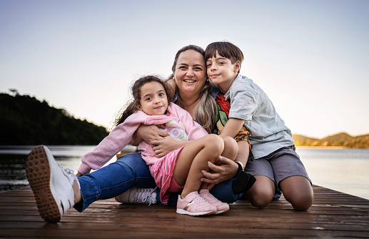 Mother and children smiling on the lake pier
