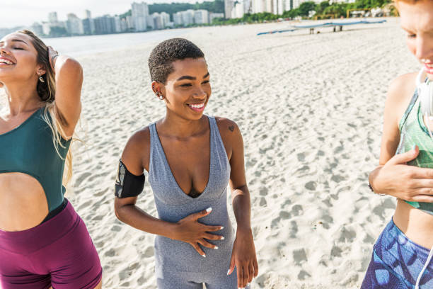 istock Three attractive women in sportswear exercise on the beach 1341148174