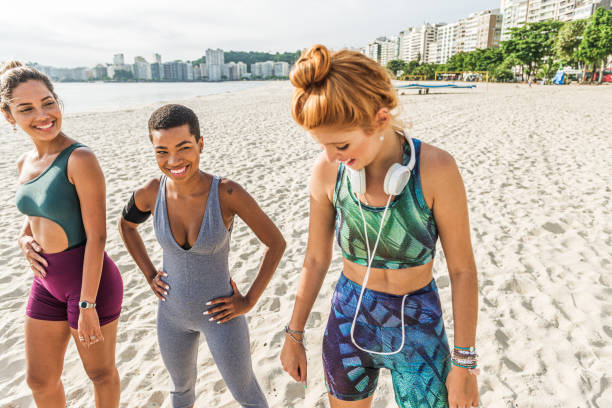 istock Three attractive women in sportswear exercise on the beach 1341148176