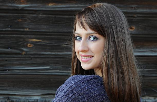 Beautiful young country  woman posing on firewood background