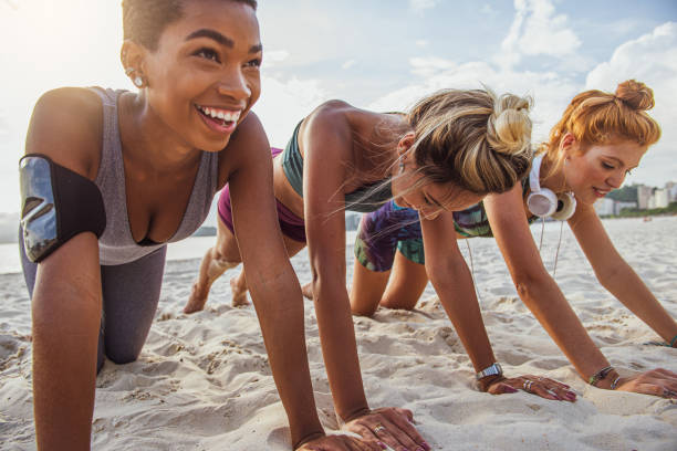 istock Three young women doing push-ups on the beach 1341149431
