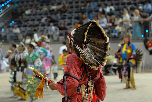 american indian in his traditional dress from behind in a pow wow