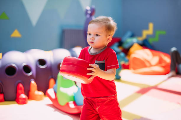 Happy laughing boy 1-2 years old having fun in ball pit on birthday party in kids amusement park and indoor play center. Child playing with colorful balls in playground ball pool. Activity toys for little kid. feliz niño risueño de 1-2 años divirtiéndose en el pozo de bolas en la fiesta de cumpleaños en el parque de diversiones para niños y el centro de juegos cubierto. niño jugando con pelotas de colores en la piscina de bolas del patio de recreo. juguet