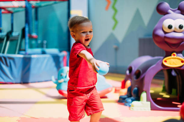 Happy laughing boy 1-2 years old having fun in ball pit on birthday party in kids amusement park and indoor play center. Child playing with colorful balls in playground ball pool. Activity toys for little kid. feliz niño risueño de 1-2 años divirtiéndose en el pozo de bolas en la fiesta de cumpleaños en el parque de diversiones para niños y el centro de juegos cubierto. niño jugando con pelotas de colores en la piscina de bolas del patio de recreo. juguet