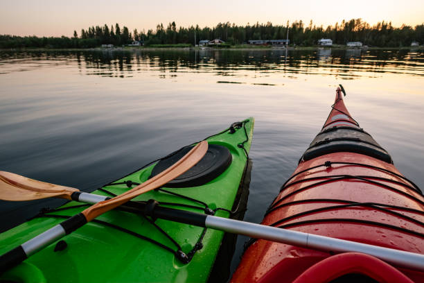 istock Two green and red wet kayaks float still together on water surface with two crossed orange paddles, summer evening, sea kayaking in Northern Sweden, Umea 1341159509