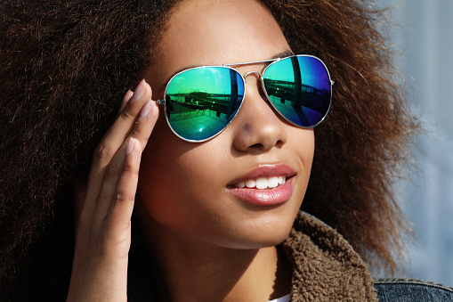 Young african american girl in sunglasses, posing outdoors, Dressed casul, with short voluminous hair.