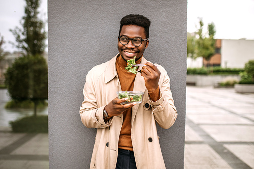 Smiling handsome businessman having lunch in a front of corporate building