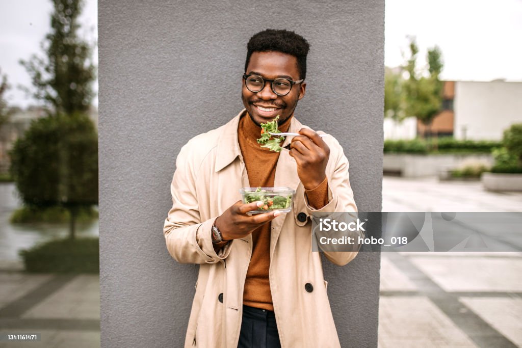 Lunch break on fresh air Smiling handsome businessman having lunch in a front of corporate building Eating Stock Photo