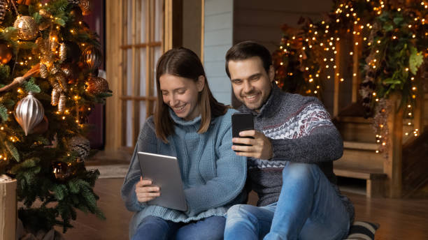 istock Addicted to tech young couple using gadgets near Christmas tree. 1341162457