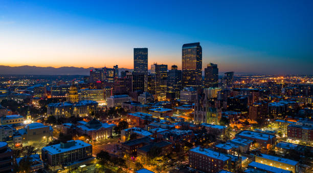 Denver Skyline Aerial At Dusk With Sunset And Mountains Downtown Denver skyline aerial at dusk with the sunset and Rocky Mountains in the far background, the metropolitan area in the background, and various buildings in the foreground including the Colorado State Capitol building in the left. denver stock pictures, royalty-free photos & images