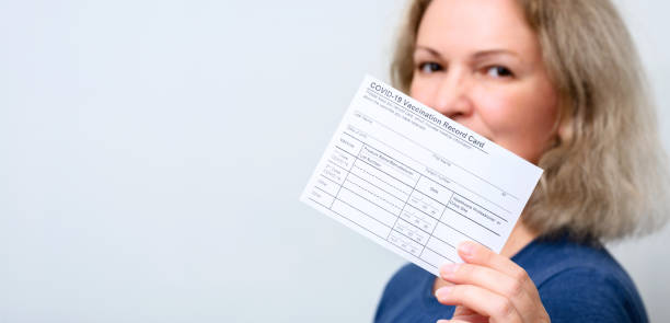 Vaccinated young woman showing COVID-19 Vaccination Record Card stock photo