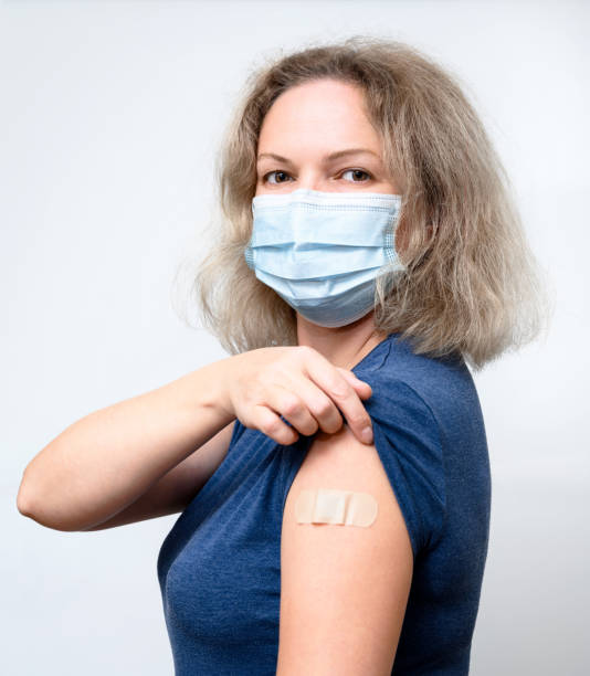 istock Vaccinated young woman showing shoulder with plaster 1341171368