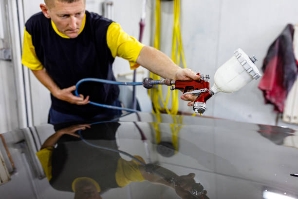 istock Young Car Mechanic is Painting a Car Using a Spray Compressor. 1341173657
