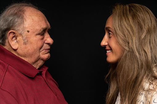 Studio portrait of a Portuguese woman with her old dad looking at each other.