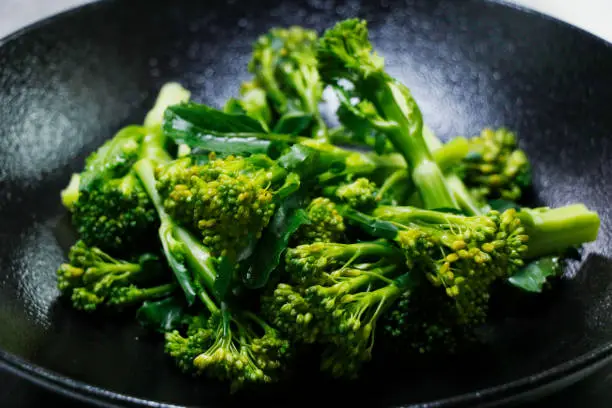 steam broccoli or broccolini with black background in close up, healthy food concept, vegetarian diet