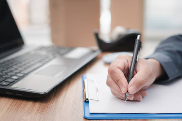 istock A man take note in clipboard while and packing post shipping box and checking website retail order using laptop preparing delivery parcel on table : online store small business 1341188016