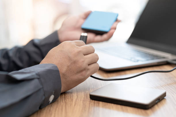 istock Business man use External disk connect to laptop computer with USB cable for Keeps important computer information in work office 1341188042