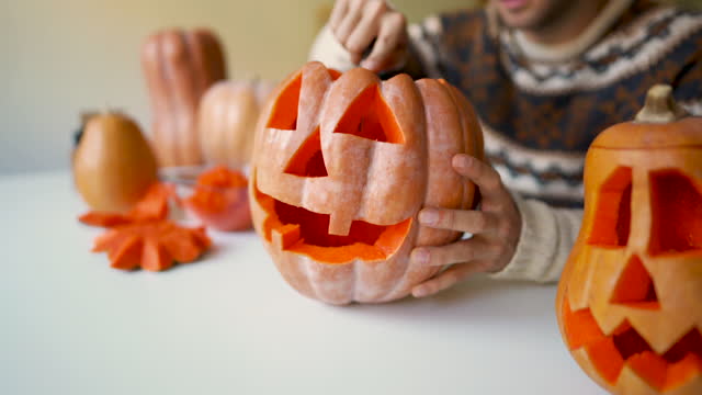 Close-up of an unrecognizable man carving a pumpkin for Halloween
