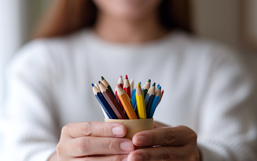 A woman holding lots of colorful colored pencils in hands