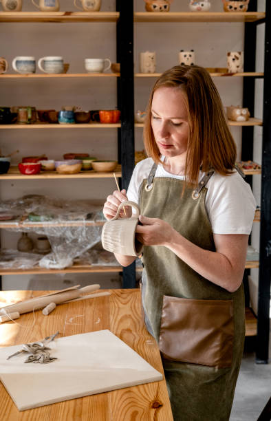 istock Woman potter in apron making pottery in studio. The master potter works in a workshop. 1341210133