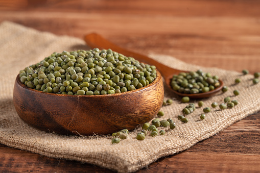 Close up of raw mung bean in a bowl on wooden table background.