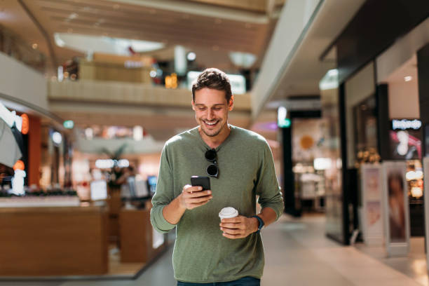 portrait of man using phone - telephone indoors retail shopping mall imagens e fotografias de stock
