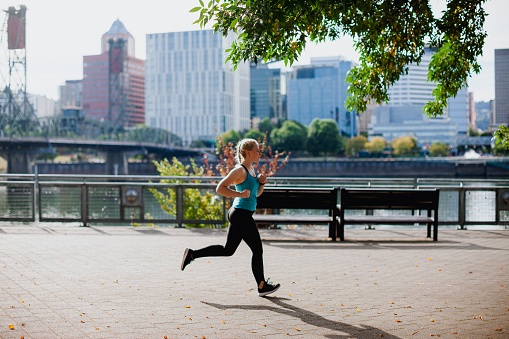 Lifestyle images of an athletic young woman runner. She is in a modern city, the Portland Oregon Skyline can be seen in the background of these images.