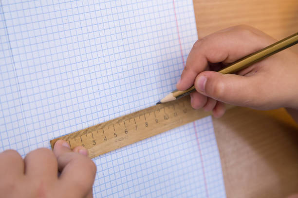 istock The student draws a figure in a notebook with a pencil along a ruler. 1341217749
