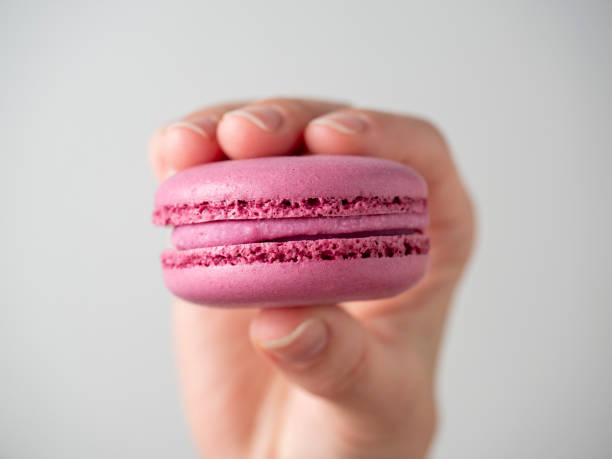 biscotti viola dolce amaretto in mano su uno sfondo bianco. primo piano, prodotto per il condizionamento dell'aria - amaretto foto e immagini stock